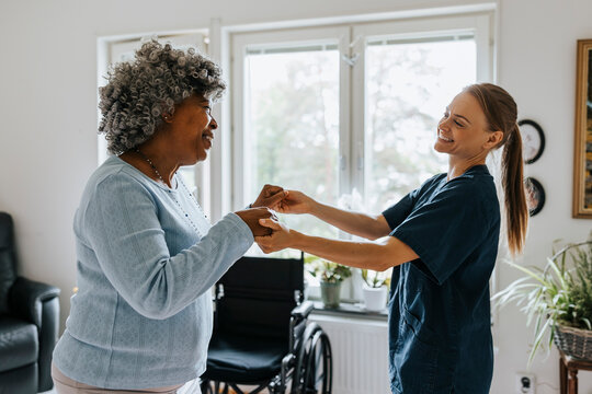Happy female doctor dancing with elderly woman at nursing home