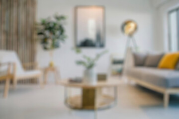 Blurred view of modern living room with sofa and soft bench. room interior with couch, armchair and coffee table or shelving units. stylish living room. comfortable workplace near big window.