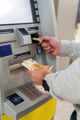 Man is withdrawing euro banknotes from an ATM after inserting and validating his credit card