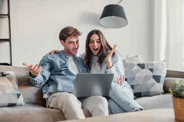 Happy emotional positive young family couple woman man looking at computer screen, celebrating...