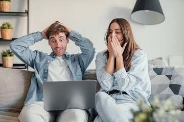 Happy emotional positive young family couple woman man looking at computer screen, celebrating...