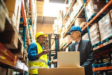 Warehouse manager and worker discussing logistics in storage facility