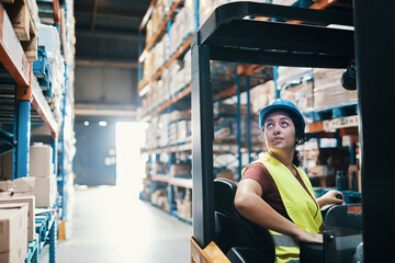 Female worker operating forklift in large warehouse