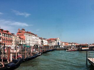 A quintessential Venetian scene. A bustling canal is lined with colorful buildings and filled with gondolas, creating a lively and picturesque atmosphere. 