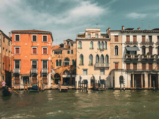 Venetian Canal with Colorful Buildings. A canal winds its way through the city, lined with colorful buildings in various shades of orange and yellow. The sky is a mix of blue and fluffy white clouds.