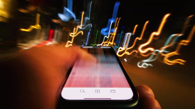 Close-up time-lapse hyperlapse of male hand scrolling social networks on smartphone screen walking city street at night, fast motion light trails, pov cellphone scrolling apps surf internet web pages