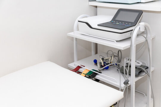 Electrocardiogram equipment for making cardiogram test of patient who is attached with vacuum sensors to the machine near coach in medical office room. Healthcare concept