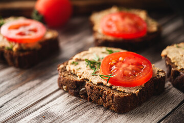 Rustic Pate, man smear on Black Bread with Fresh Herbs and tomatoes