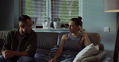 A man and a woman are talking with an offended look while sitting on the couch. A family quarrel....