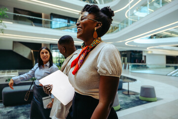 Friendly African businesswoman with colleagues in modern office lobby