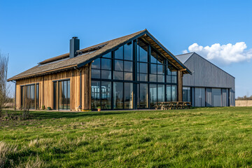 Obraz premium Modern barn-style home with expansive windows and attached structure.
