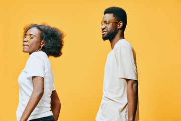Obraz premium Stylish young African American couple in casual wear on a vibrant yellow background, showcasing confidence and joy while posing together