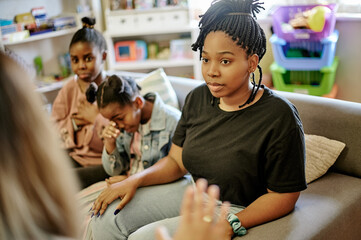 Black family, therapy or counseling with and mother and children talking to a psychologist for child development. Psychology, kids or communication with a woman and daughters meeting a therapist