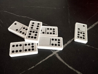 A set of dominoes is casually scattered across the table, some pieces overlapping while others rest at odd angles.