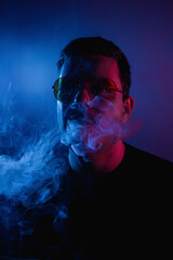 Neon-lit atmosphere surrounds a man smoking, creating a mesmerizing cloud of smoke in the air