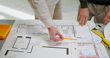The foreman studies the building plan with the client. Close-up of the plan, unrecognizable persons
