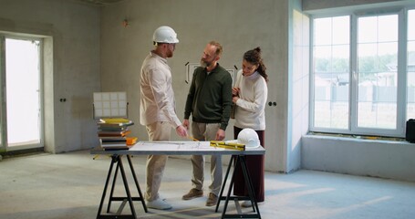 The foreman negotiates the dimensions with the clients at the construction site. He uses a roulette...