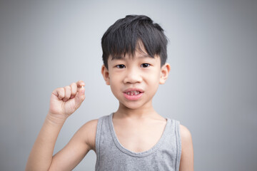 6 years old Asian boy showing his lost tooth, proud of his gap.