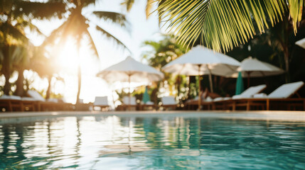 Palm trees and umbrellas surround a tranquil swimming pool at a tropical resort, creating a relaxing and luxurious vacation atmosphere at sunset. Blurred backdrop