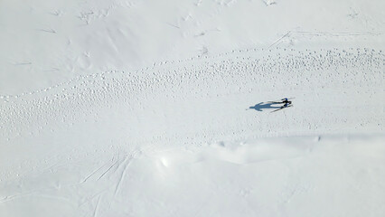 Aerial View of Skier on Snowy Terrain. Top-down view of a lone skier gliding across a vast snowy...