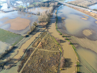 Vue aérienne prise avec un drone montrante rivière en crue qui déborde et un paysage inondé.