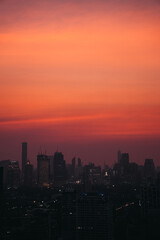 Obraz premium Dark silhouettes of Bangkok's buildings rising against an expressive, intense orange sunset sky, creating a dramatic urban landscape, Thailand