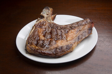 Sizzling t-bone steak grilling, served on pristine white ceramic plate