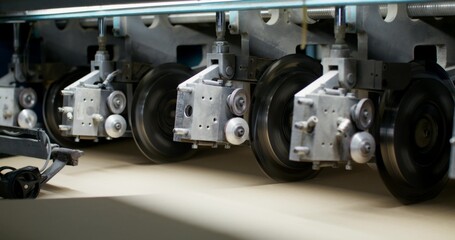 Production of cardboard. A close-up of the details of the machine for the production of cardboard in the factory. Cutting of cardboard sheets