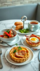 Tasty breakfast spread featuring savory tarts, chicken balls, and tea served on a marble table