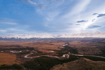 Panoramic view of serpentine river and snow-capped mountains in Altai, Siberia