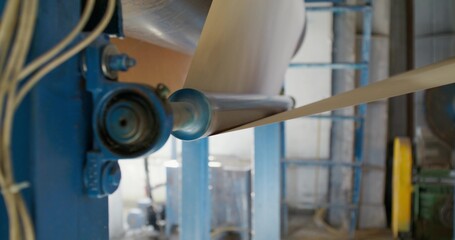 A paper factory. Close-up of the machine part. A strip of paper passes through a spool