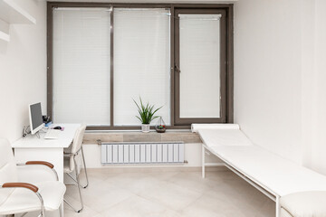 View of modern medical office with doctor's workplace in clinic. Modern medical office with doctor's workplace and examination table in clinic