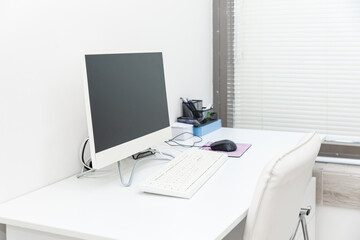 Doctor's workplace with computer. Interior of modern medical office. Empty doctor's office with white furniture and walls. Copy space