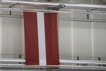 Large national Latvia flag haning on sidewall in Ice Hockey Arena.