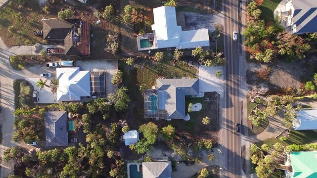 Rows of houses, resorts, rental properties, and various residential buildings on beachfront Sanibel Island, FL near Florida vacation Ocean beachfront resort with coastline from drone aerial view