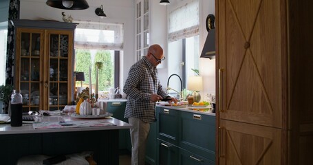 The man cooks his own food. He carries a full plate to the table. Daylight