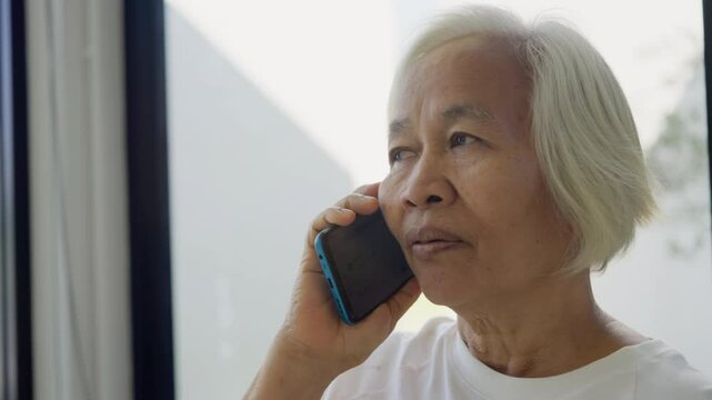 Phone scam call target talk old asian female cyber crime fraud alert on older people. Mature adult retired woman asia parent avoid look at text threats mobile buy pay online banking app social media.