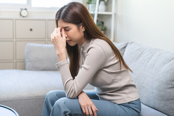 Depressed anxiety asian young woman, girl frustrated closed eyes, touching nose suffering stressed, sick, tired, crisis sitting on sofa from headache, migraine pain tension problem health care concept