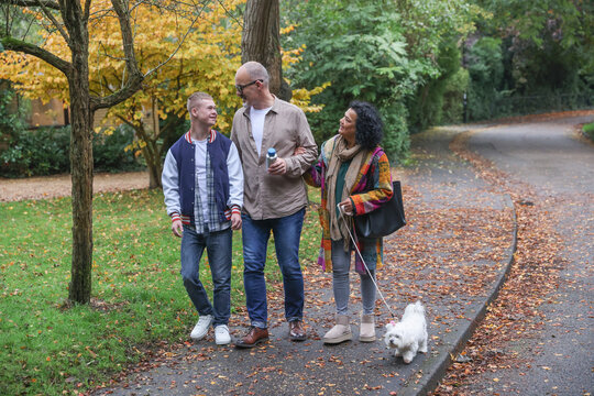 Family with adult son walking dog in autumn