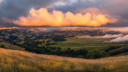 Fototapeta premium mountain vista at golden hour, dramatic clouds catching sunset light, rolling hills fade into misty valleys, majestic peaks reflect warm amber glow
