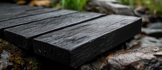 Fototapeta premium Close-up of wet wooden planks with natural stones and blurred greenery in background