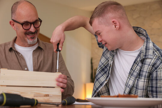 Father helping adult son to put together wooden box