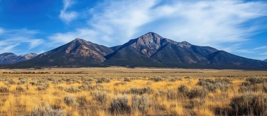 Fototapeta premium Mountain Range with Blue Sky and Grassland in Foreground