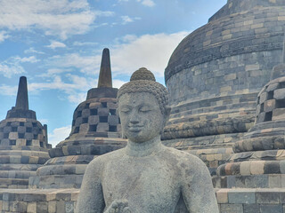 Ancient Stone Buddha Statue of Borobudur Temple at Yogyakarta Stands Serene before a Majestic...