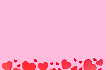 Valentine day pink background with red hearts, assorted red hearts layout simple pattern on pastel pink background, top view copy space. Valentine`s day invitation, menu, greeting card 