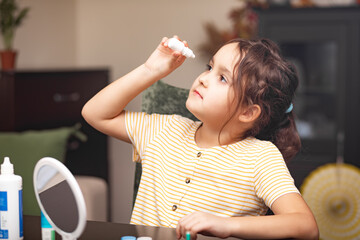 Cute little girl inserting contact lenses into her eye. Vision correction and ophthalmology for...