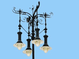 Very nice four-branched cast iron street lamp in front of a blue sky.