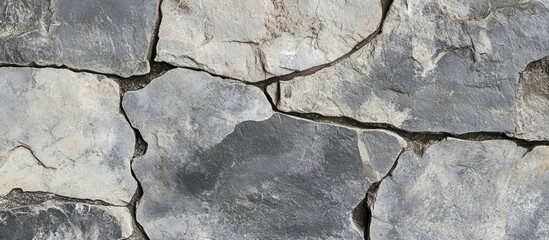 Fototapeta premium Textured surface of uneven gray stone wall with visible cracks and crevices suitable for background or architectural design use Copy Space