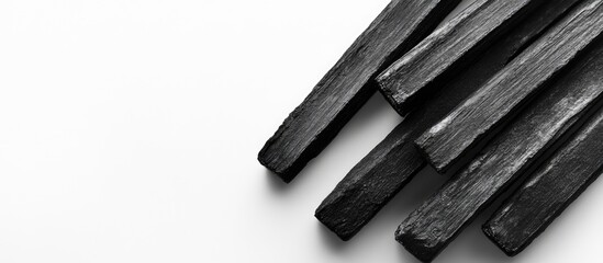 Black charcoal sticks arranged on a minimalist white background with copy space for text placement