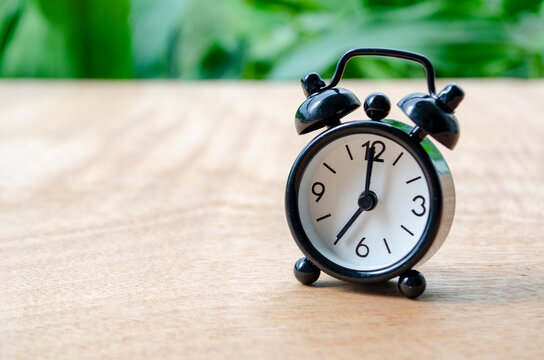 Table alarm clock pointing at 7pm or 7am with customizable space for text. Time management concept and copy space.